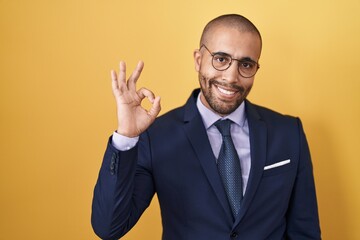 Hispanic man with beard wearing suit and tie smiling positive doing ok sign with hand and fingers. successful expression.