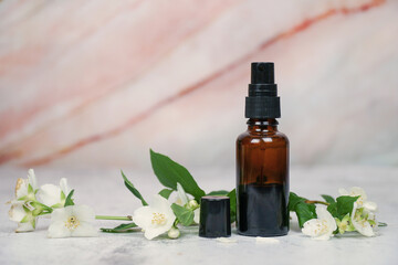          Jasmine natural face and body mist in amber spray bottle with fresh jasmine flowers on marble background.        