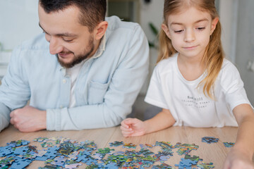 happy family playing with puzzle pieces at home. Focus on girl.