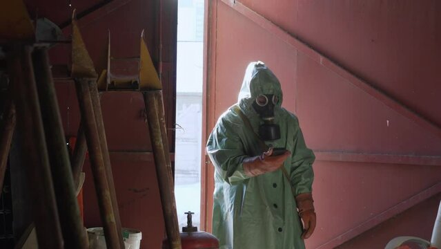 Person wearing protective suit with radiation dosimeter in hands inspection pollution level indoor of abandoned building.