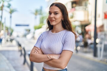 Young woman smiling confident standing with arms crossed gesture at street
