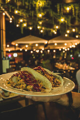 Deliciosas Tortillas Mexicanas rellenas de carne, salsa y verduras, en un precioso bar nocturno decorado con luces cálidas