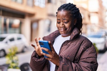 African american woman using smartphone with serious expression at street