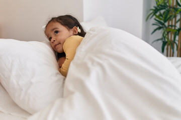 Obraz na płótnie Canvas Adorable hispanic toddler smiling confident lying on bed at bedroom