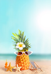 Pineapple with sunglasses and flower on tropical beach background. Summer beach concept.