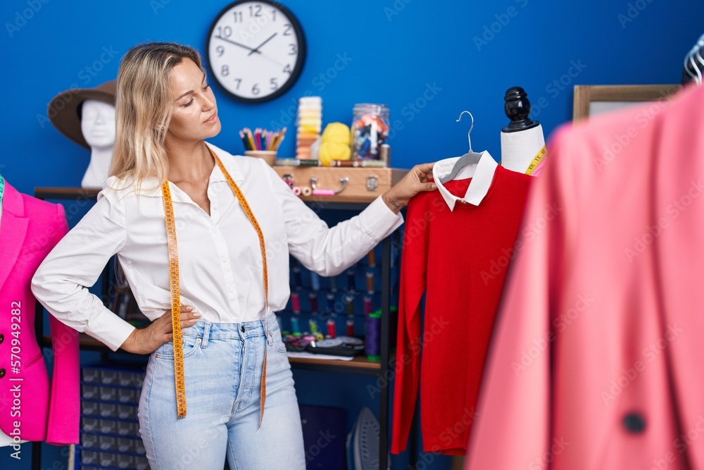 Sticker Young blonde woman tailor holding t shirt at tailor shop