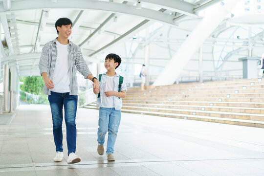 Father Taking His Son Going To School, A Man Holding Child Hand While Walking To School Together.