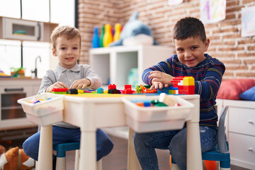 Two kids playing with construction blocks sitting on table at kindergarten