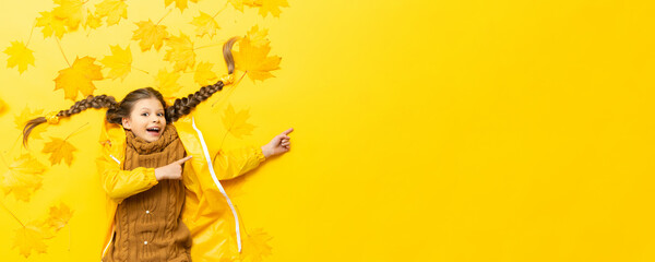 The girl has an autumn mood, a little beautiful girl on a yellow background with maple leaves.