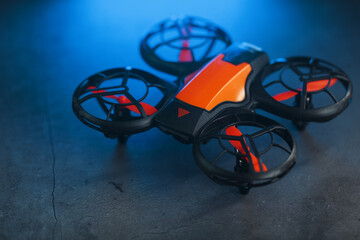 Orange quadcopter mini spy drone on a dark background with blue backlight