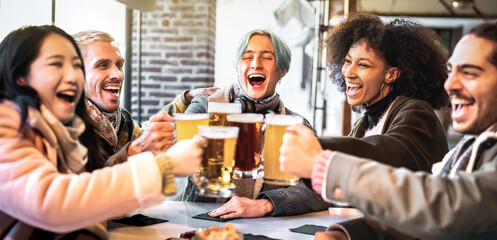 Happy friends group drinking and toasting beer at brewery bar restaurant - Food and beverage concept with young diverse people having fun together at vintage pub garden - Focus on middle guy
