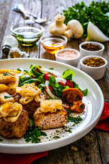 Fried pork meatballs with fried onion, french fries and fresh vegetables on wooden table
