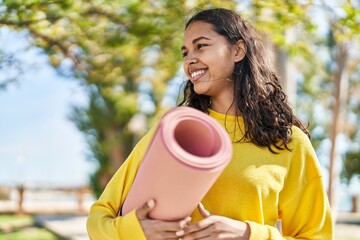 Young african american woman smiling confident holding yoga mat at park