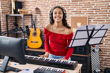 Young african american woman musician playing piano keyboard at music studio