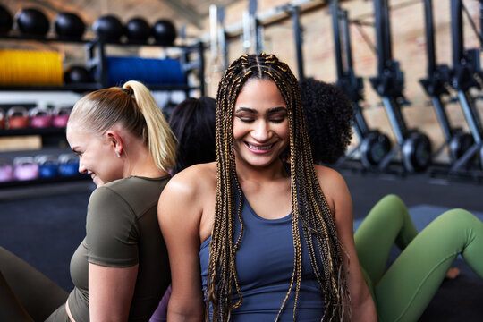 Diverse young female friends laughing at the gym. People in gym exercising.