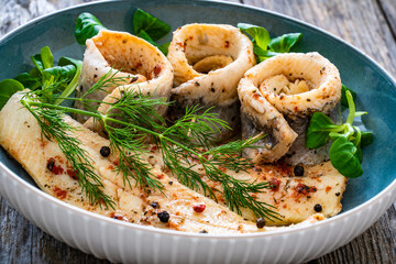 Marinated herring fillets with dill on wooden table

