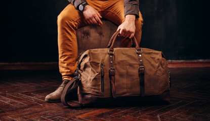 Men's accessories . Man holding Brown leather and canvas bags in hand.