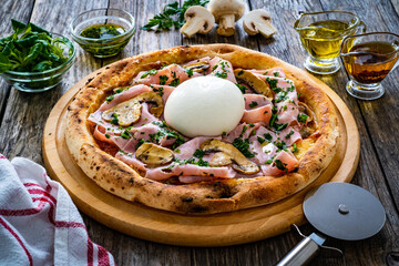 Circle prosciutto burrata pizza with mushrooms on wooden table
