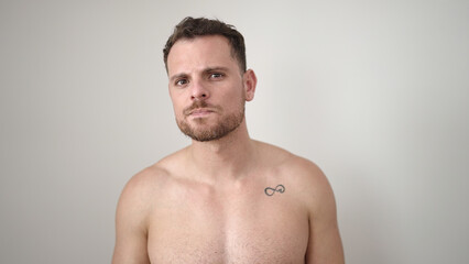 Naklejka premium Young caucasian man standing shirtless with serious expression over isolated white background