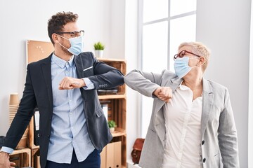 Mother and son business workers wearing medical mask make elbow greeting at office