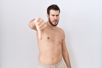 Fototapeta premium Young hispanic man standing shirtless over white background looking unhappy and angry showing rejection and negative with thumbs down gesture. bad expression.
