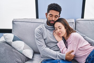 Man and woman couple hugging each other lying on sofa at home