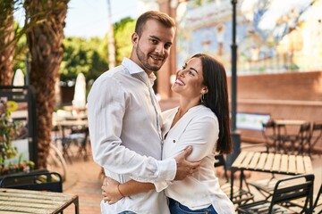 Man and woman couple smiling happy hugging each other standing at street