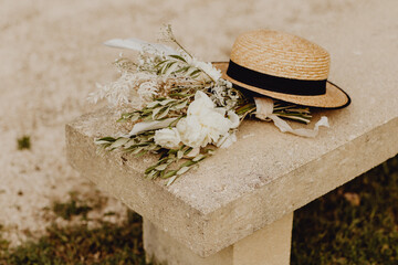 Bouquet de fleurs déposé sur un banc avec un chapeau de paille