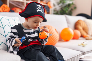 Adorable hispanic boy having halloween party holding pumpkin basket and car toy at home