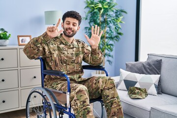 Fototapeta premium Arab man wearing camouflage army uniform sitting on wheelchair showing and pointing up with fingers number seven while smiling confident and happy.