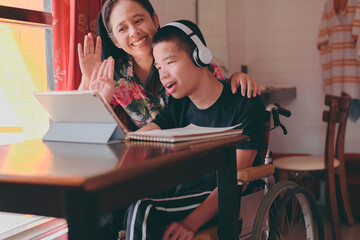 Fototapeta na wymiar A smart young man with a disability on wheelchair smiling face using social media with parent to learning distance,Teenage boy use technology,social media,live,video chat,remote education,Homeschool.