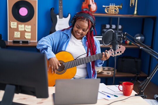 African american woman musician singing song playing classical guitar at music studio