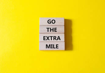 Go the extra mile symbol. Wooden blocks with words Go the extra mile. Beautiful yellow background....