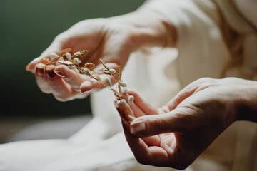 Accessoire pour les cheveux en perles et céramique dans les mains de la mariée
