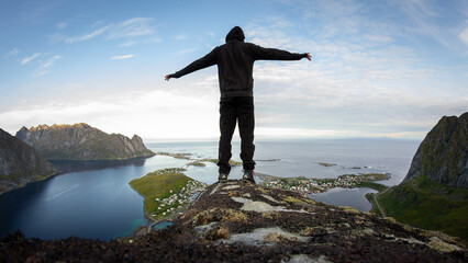 Hiker reaching the top of a mountain in Lofoten, Norway