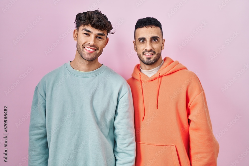 Sticker young hispanic gay couple standing over pink background with a happy and cool smile on face. lucky p