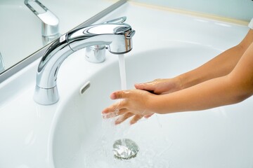 洗面所の蛇口で手を水洗いする子供の手