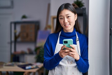 Chinese woman artist smiling confident using smartphone at art studio
