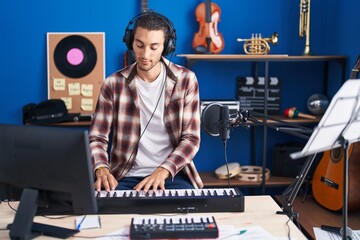 Fototapeta na wymiar Young hispanic man musician playing piano at music studio