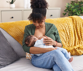 Mother and son sitting on sofa breastfeeding at home