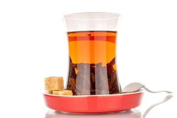 A few cubes of brown sugar with a glass of black tea and a metal spoon, macro, isolated on a white background.