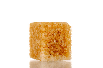 One cube of brown sugar, macro, isolated on white background.