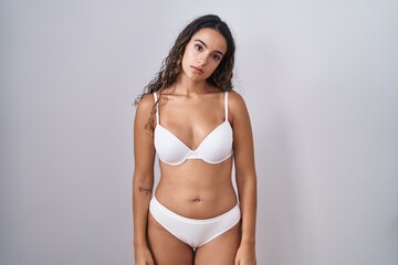 Obraz premium Young hispanic woman wearing white lingerie looking sleepy and tired, exhausted for fatigue and hangover, lazy eyes in the morning.