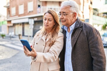 Middle age man and woman couple smiling confident using smartphone at street