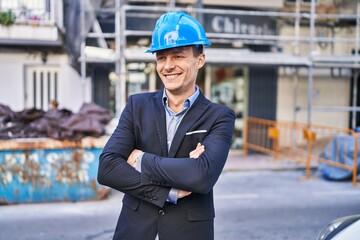 Young man architect smiling confident standing with arms crossed gesture at street