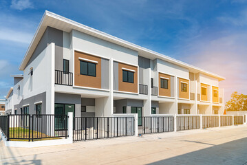 The row of just-finished new townhouses the Concept of buying a house vs renting an apartment, architectural design of exterior townhomes with blue sky.