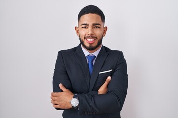 Young hispanic man wearing business suit and tie happy face smiling with crossed arms looking at the camera. positive person.