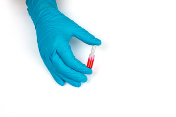 The doctor's hand in medical blue gloves holds an ampoule with medicine, close-up.