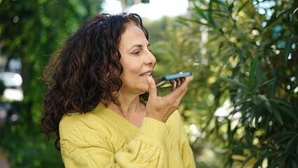 Middle age hispanic woman smiling confident talking on the smartphone at park