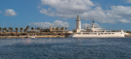 Panoramic view of the port of the city of Malaga on the Mediterranean sea, with historic lighthouse and luxury yacht. 